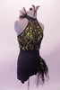 Short unitard is a halter style with a black short bottom. The top is a lime green with black sequined lace overlay. Two vertical straps extend from the back of the neck to support the back. There is a ruffled tulle accent at the left side of the neck that matches the ruffle accent at the left hip. Right side