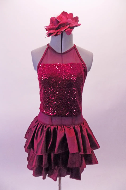Deep burgundy halter neck leotard dress has a sequined torso. And sheer waist and ruffled layers of taffeta skirt. The open back has double vertical bands extending from the collar. Comes with a large burgundy floral hair accessory. Front
