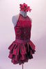Deep burgundy halter neck leotard dress has a sequined torso. And sheer waist and ruffled layers of taffeta skirt. The open back has double vertical bands extending from the collar. Comes with a large burgundy floral hair accessory. Side