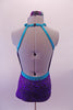 Purple and pewter leotard has an intricate swirl design throughout. The costume has a halter neck with an oval opening at the front center & completely open back. The bright splash of turquoise is evident in the braided banding that accents the front torso, collar, waist & neck straps. Comes with a floral accessory. Back