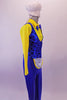 3-piece costume has a bright yellow button front collared shirt with attached blue bow tie. A blue pinstripe black polka dot vest that gathers at the back sits over the shirt & compliments the blue stretch fabric trousers with an attached white mini apron. Comes with white plush chef hat accessory with elastic. Right side