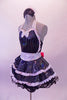 Waitress themed, 2-piece shiny black costume has sweetheart bust with halter neck. The silver sequined straps, bow tie & waistband give the costume sparkle. White lace ruffles accent the layers of the skirt with a black petticoat. The back is open with a large pink sequined bow. Comes with waitress hat accessory. Side