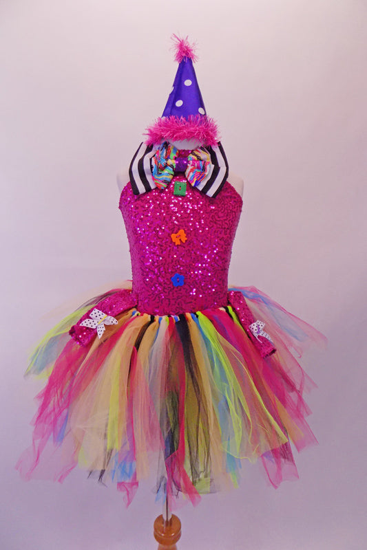 Fuchsia sequined leotard has a large round keyhole back, colourful multi-shaped buttons on the torso & a large black and white striped bow tie with a rainbow accent at the front. The multicoloured rainbow tie-knot, knee-length tutu skirt pulls on top with. Comes with purple polka dot party hat with pink feather trim. Front