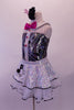 Music-themed leotard with black and silver swirled torso with white shoulders, collar & sheer back. There is a shiny vertical white stripe down the center of the torso with hot pink jewelled buttons that match the bow tie. The silver sequined skirt with white petticoat has black edge & musical note appliques. Left side