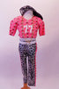Two-piece football themed costume has a half top with a geometrical pattern of pinks & reds, Shoulders are padded with number “77” on the front & the back is a black leatherette mesh. The black & white shatter print ¾ leggings have a matching pink geometrical stripe on sides. Has black fingerless gloves & baseball cap. Front