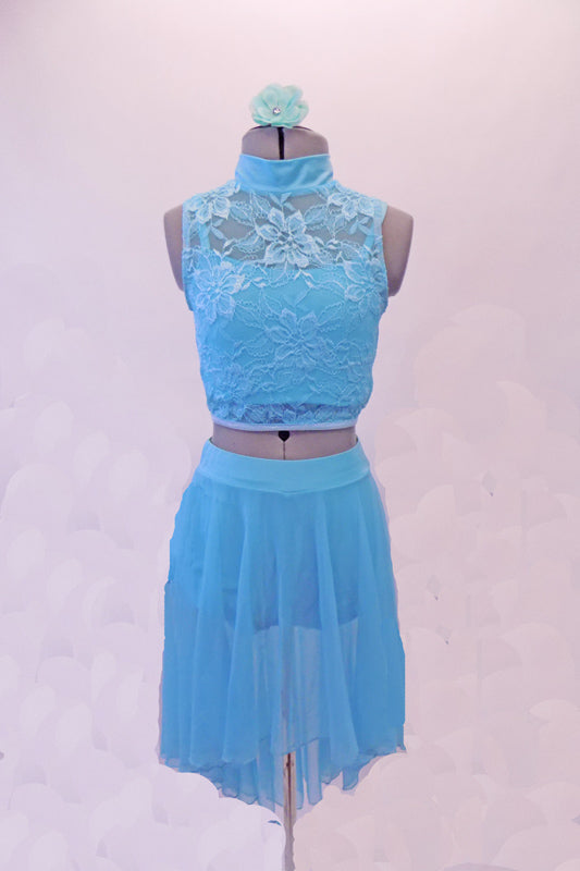 Two-piece aqua costume has floral lace high neck haft top with peek-a-boo back. Beneath the lace is an attached aqua camisole. The sheer mesh skirt aqua skirt is longer at the back and has an attached brief. Comes with a floral hair accessory. Front