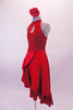 Two-piece costume has a glittery red halter neck leotard with front peek-a-boo loop at the chest. The open upper back had four thin vertical straps that join to the neck cuff. The accompanying red satin skirt is a wrap with large ruffle. The skirt opens at the side and is reinforced by two velcro bands. Has red flower. Side