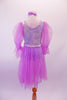 Lavender leotard-based Empire dress has a floral print bodice with silver sequined trim. Large pouffe and ruffled sheer sleeves and attached knee-length skirt give the dress a pretty flow on stage. The bodice has large ivory rose accent and a matching floral and ribbon headband. Back