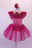 Pink and burgundy ballet dress has a wide burgundy ruffle collar circling from front to back along the nude bust. A sequined trim lines the ruffle and there is a band of roses along the front. The pink torso has an attached burgundy sheer skirt. Comes with matching floral hair accessory. Front