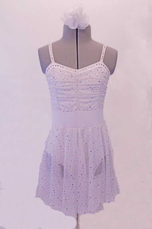 White dress has scattered glitter sequins throughout the fabric. The bodice is ruched to add softness and depth. Crystals line the entire banding of the bustline and straps. Comes with a hair accessory. Front