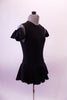 Black leotard dress has a short flowy peplum skirt that attaches in a low front/back princess cut waistline. The back is an open keyhole. Comes with ruffled armband accessory. Side