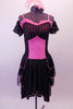 Saloon themed dress has a pink torso overlain by sheer black stripes at bust, sides and back. The knee-length skirt has triple-layered black peplum bustle. Pink ruffles accent the sweetheart neckline. Comes with black sheer striped pull-on sleeves and feathered hair accessory. Front