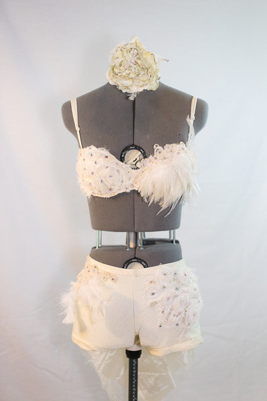 Custom designed, ivory bra, and shorts with intricate appliqué, beading, feathers, and  crystals. Back has tail of layered tulle, crystals and rose fabric, front