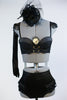 Black bustier style bra with fringed epaulets and gold chain details. at front. Has ruffled, high-waisted panty, long black gloves and a black head piece. Front zoom