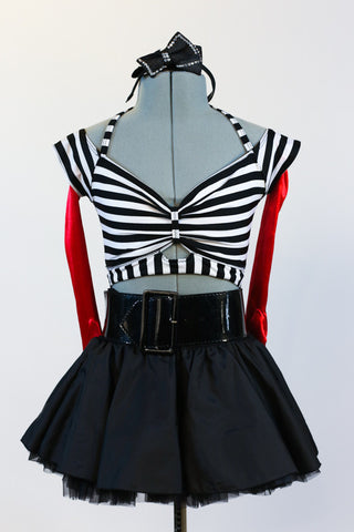 Striped, crop-top with neck-strap and short black, crinoline lined taffeta skirt, wide black patent leather belt, long red gloves and black bow headband. Zoomed