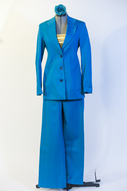 Fully lined turquoise suit has button front which can be worn open or closed. Comes with gold metallic half top worn underneath & matching floral hair accessory. Front