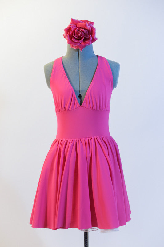Pink, halter leotard dress has cross straps and low back. Has wide waistband, triangle style bust area & gathered skirt. Comes with matching floral hair piece. Front